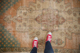 Textured vintage Distressed Oushak rug pile with worn terra cotta, beige, and teal geometric motifs.