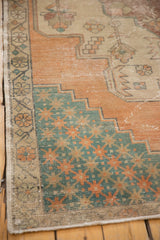 Vintage Turkish Oushak rug corner showing distressed terra cotta field, exposed foundation, and teal starbursts.