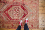 Distressed cherry red stepped medallion and faded beige pile textures of a vintage Oushak rug.