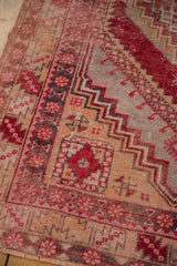 Distressed Oushak rug featuring cherry red serrated leaves and beige floral cartouche motifs.