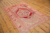 Distressed Oushak rug corner with cherry red serrated leaf border, geometric inner motif, and secured end.