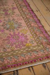 Distressed texture on vintage Oushak rug's blush, fuchsia, mint green, and yellow border.