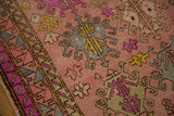Textured blush vintage Oushak rug with florescent purple, saffron yellow gul motifs.