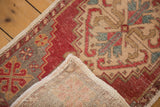 Corner fold of vintage Oushak rug, revealing hand-knotted foundation and even pile wear.