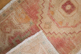 Hand-knotted vintage distressed Oushak rug corner, revealing short fringe and visible foundation.