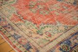 Distressed Oushak rug corner with brick red field, worn ivory, royal blue, and mint green motifs.