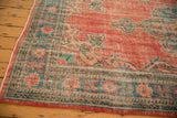 Distressed Oushak carpet border showing brick red, denim blue, and beige floral-geometric motifs.