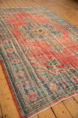 Vintage distressed Oushak rug end, brick red field, denim blue border, secured fringe.
