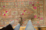 Distressed vintage Oushak runner, highlighting bright pink pinwheel motifs and visible foundation wear.