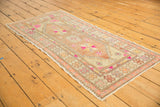 Close-up of vintage Oushak runner end, ivory border, bright pink motifs, visible wear, and fringe.
