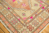Distressed Oushak rug corner detail, revealing geometric border and playful pink accents.
