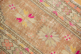 Distressed Oushak rug shows textured pile with visible foundation, dusty copper and bright pink.