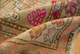 Worn texture of a vintage distressed Oushak rug runner, showing vivid pink and copper motifs.