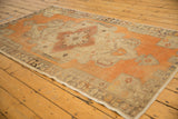 Distressed Oushak rug side, tangerine orange, beige, and burgundy geometric floral vinery.