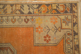 Distressed tangerine orange Oushak rug corner with beige border, budded floral vinery.