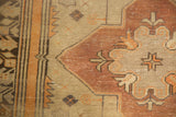 Distressed Oushak rug runner close-up: geometric vinery, tangerine, burgundy, ivory, and faded wear.