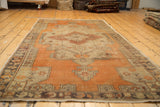 Distressed tangerine orange and beige vinery on vintage Oushak rug corner.