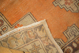Distressed tangerine orange pile of a vintage Oushak rug with geometric pattern and secured fringe.