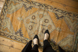 Distressed vintage Oushak rug displaying even wear, dusty gold, ivory, and charcoal tones.