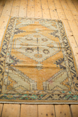 Distressed Oushak rug's pile texture with even wear and exposed foundation in dusty gold and charcoal.