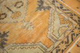 Distressed Oushak rug corner showing geometric border, worn pile, charcoal, dusty gold, and ivory.