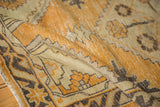Folded vintage Oushak rug, distressed with dusty gold and charcoal geometric patterns.