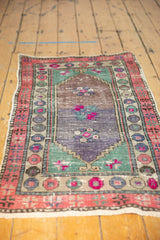 Textural abrasions and vibrant pink floral motifs on the distressed field of a vintage Oushak rug.