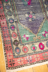 Close-up of heavily abrashed Oushak runner, showing distressed pink, purple, blue pomegranate border.