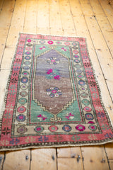 Distressed Oushak runner corner with vibrant pink pomegranate border and fringe.