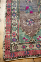 Distressed Oushak runner border with abrashed mauve field, fuchsia, and blue floral details.