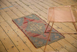 Distressed Oushak rug corner revealing muted blush, grey-blue patterns, and mostly even wear.
