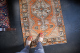 Distressed vintage Oushak rug runner, faded tangerine orange, geometric motifs and worn texture.