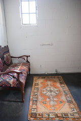 Distressed Oushak runner, faded tangerine orange field with visible textured geometric motifs.
