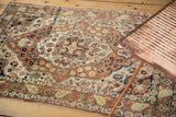 A lifestyle view of the antique Haji Jalili Tabriz rug's floral medallion in rust and ivory.