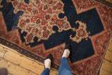 Textured pile of antique Malayer rug with abrashed indigo, vibrant red motifs, and even wear.