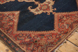 Antique Malayer rug corner, displaying its geometric tomato red border and abrashed indigo field.