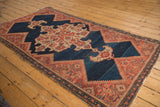 Antique Malayer rug's secured end, featuring abrashed indigo, bold red finial, and patterned border.