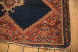 Persian Malayer rug corner, showing bright red border, dark indigo field, and secured worn end.