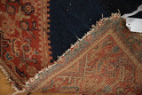 Antique Malayer rug detail of red patterned pile, woven foundation, and secured, worn end.