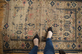 Antique Caucasian rug's geometric plant motifs, navy blue, blush, and exposed foundation.