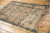 Visible foundation, secured fringed edge, and navy geometric plant motifs of the antique Caucasian rug.
