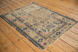 Corner of an antique Caucasian rug displaying geometric patterns in navy, blush, and ivory with hard wear.