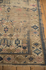 Geometric navy blue border and worn field patterns of an antique Caucasian rug.