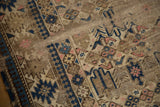 Detail of antique Caucasian rug's worn pile and foundation, featuring navy and blush geometric motifs.