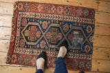 Antique Kurdish rug, showing navy and red triple lattice medallions with visible mending.