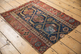 Fragmented end of antique Kurdish rug with colorful mended section and traditional motifs.
