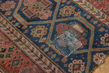 Kurdish antique rug's indigo blue field, floral motifs, and visible secured patch.