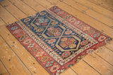 Secured end of an antique Kurdish rug, showcasing madder red border and navy motifs.