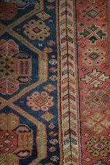 Stylized germinating plant motif border on an antique Kurdish rug with navy and red fields.