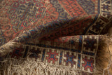 Antique Caucasian rug end, madder red, navy geometric patterns, pile wear, and tattered fringe.